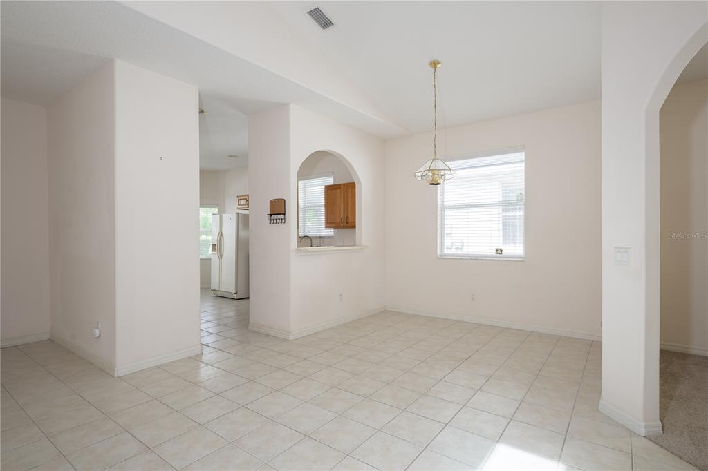 A dining area with tile flooring, a hanging light fixture, and an arched kitchen pass-through — 708 CRESTWOOD DRIVE, ST AUGUSTINE, FL