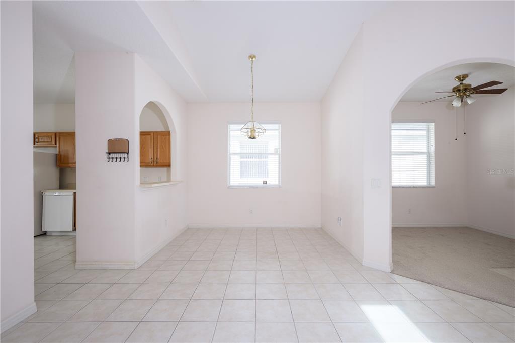 A dining area with tile flooring, a central pendant light, and an arched kitchen pass-through — 708 CRESTWOOD DRIVE, ST AUGUSTINE, FL
