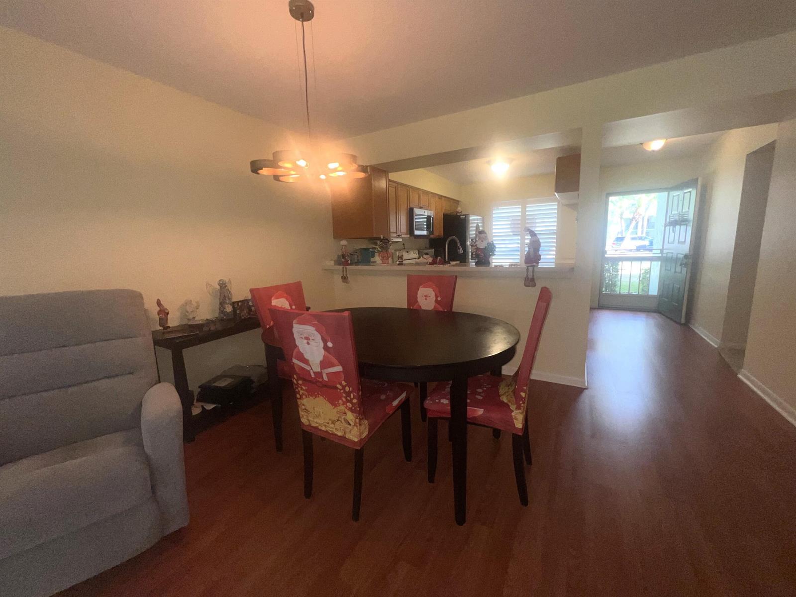 A dining area with a round table, Santa-themed chair covers, and an adjacent kitchen — 1601 Sabal Ridge Circle # C, Palm Beach Gardens FL 33418, PALM BEACH GARDENS, FL