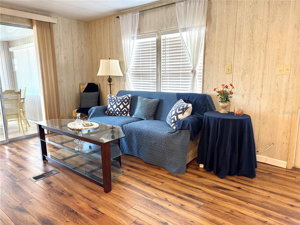 A living room features wood-paneled walls, wood-look flooring, a blue sofa, and a glass coffee table — 340 PEACE MANOR, PALMETTO, FL