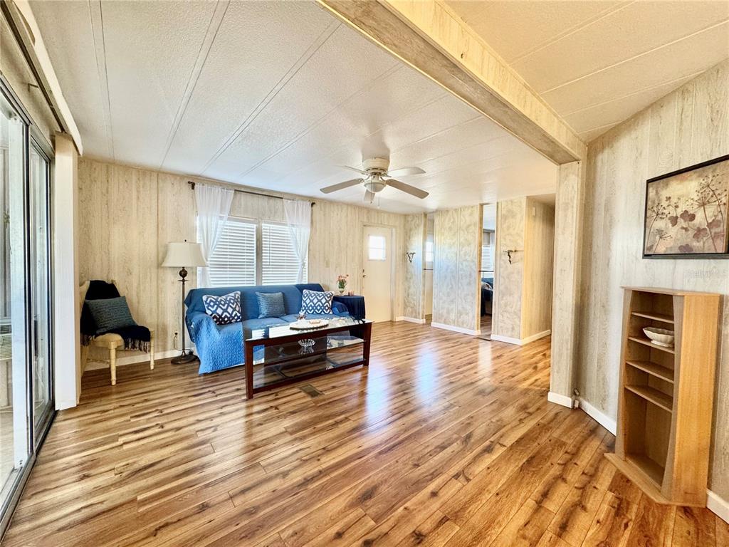 A living room features wood-look flooring, wood-paneled walls, a blue sofa, and a ceiling fan — 340 PEACE MANOR, PALMETTO, FL