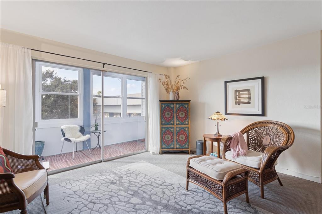 A living room features wicker chairs, a patterned cabinet, and a sliding door to a balcony — 841 4TH AVENUE N UNIT 32, ST PETERSBURG, FL
