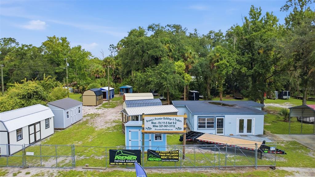 An aerial view shows a lot featuring several portable storage buildings and a small house — 2819 W STATE ROAD 44, DELAND, FL
