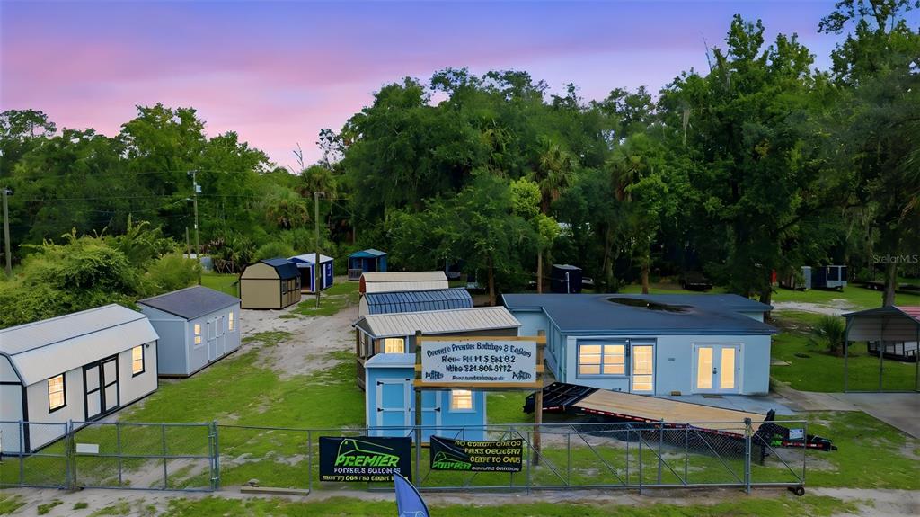 An aerial view shows a light blue building and several portable storage sheds on a lot — 2819 W STATE ROAD 44, DELAND, FL