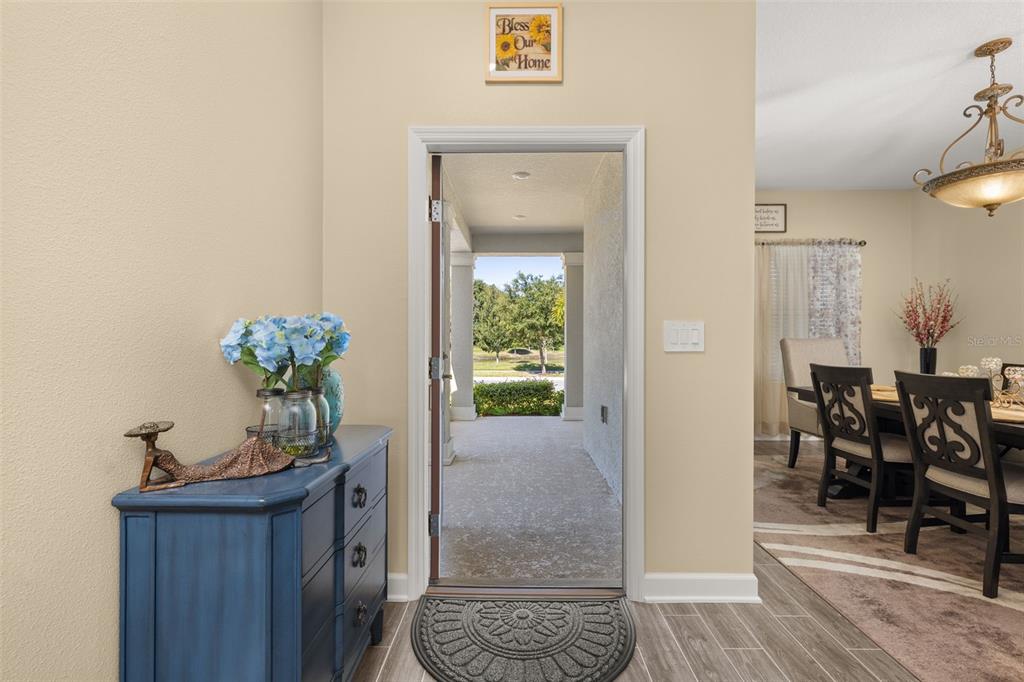 An entryway features a blue chest, a doorway leading to a porch, and a dining area — 1739 GOOD NEIGHBOR LOOP, KISSIMMEE, FL