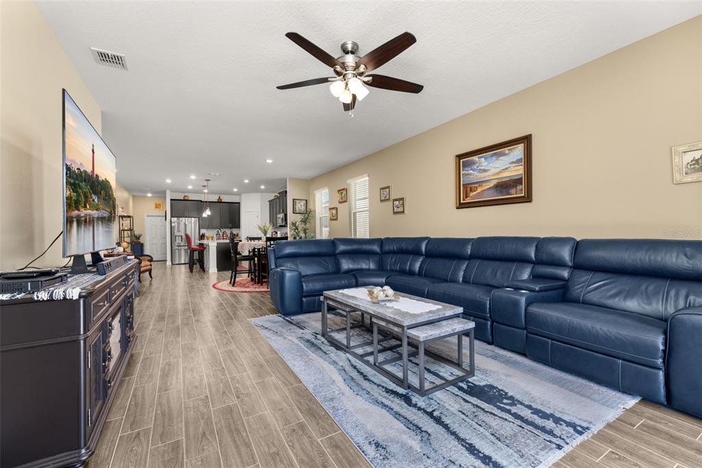 A living room features a large blue leather sectional, a coffee table, and a television — 1739 GOOD NEIGHBOR LOOP, KISSIMMEE, FL