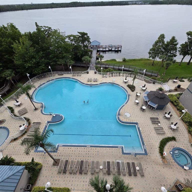 An aerial view of a swimming pool and hot tub overlooking a lake with a pier — 13427 BLUE HERON BEACH DR UNIT 1405, ORLANDO, FL