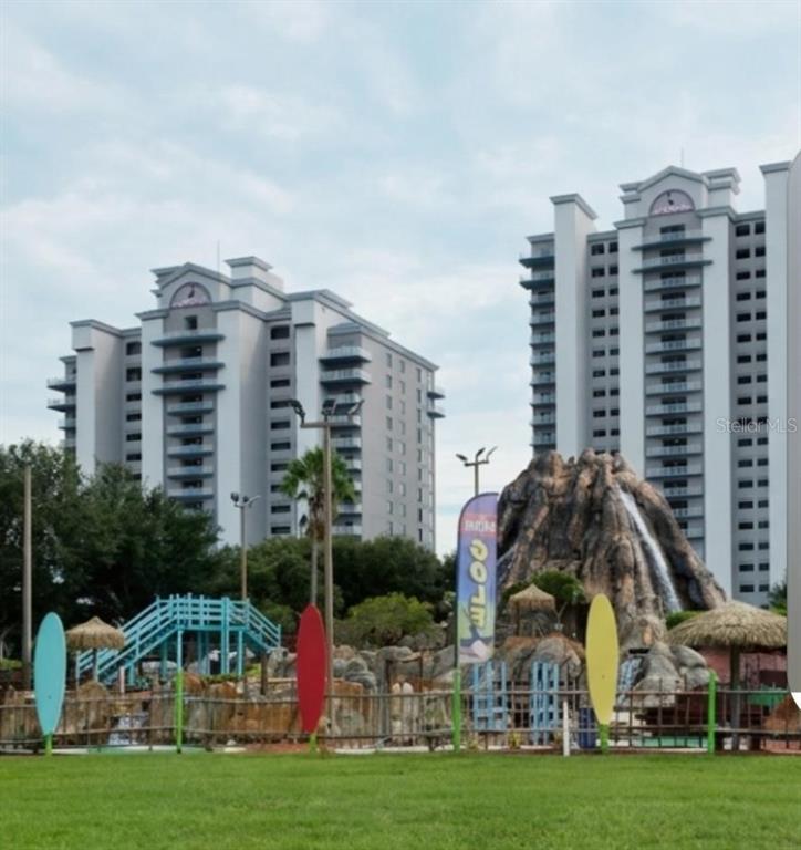 Two tall apartment buildings stand behind a miniature golf course with a volcano water feature — 13427 BLUE HERON BEACH DR UNIT 1405, ORLANDO, FL