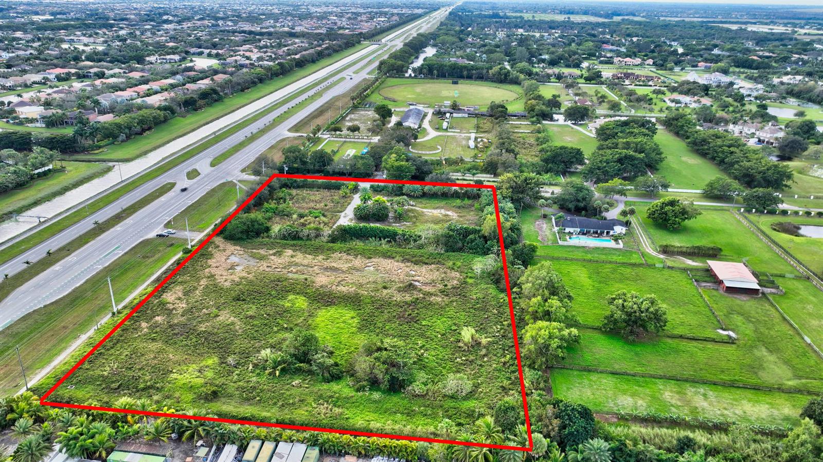 An aerial view shows a large, rectangular vacant lot outlined in red next to a highway — 15445 S State Road 7 Road, Delray Beach FL 33446, DELRAY BEACH, FL