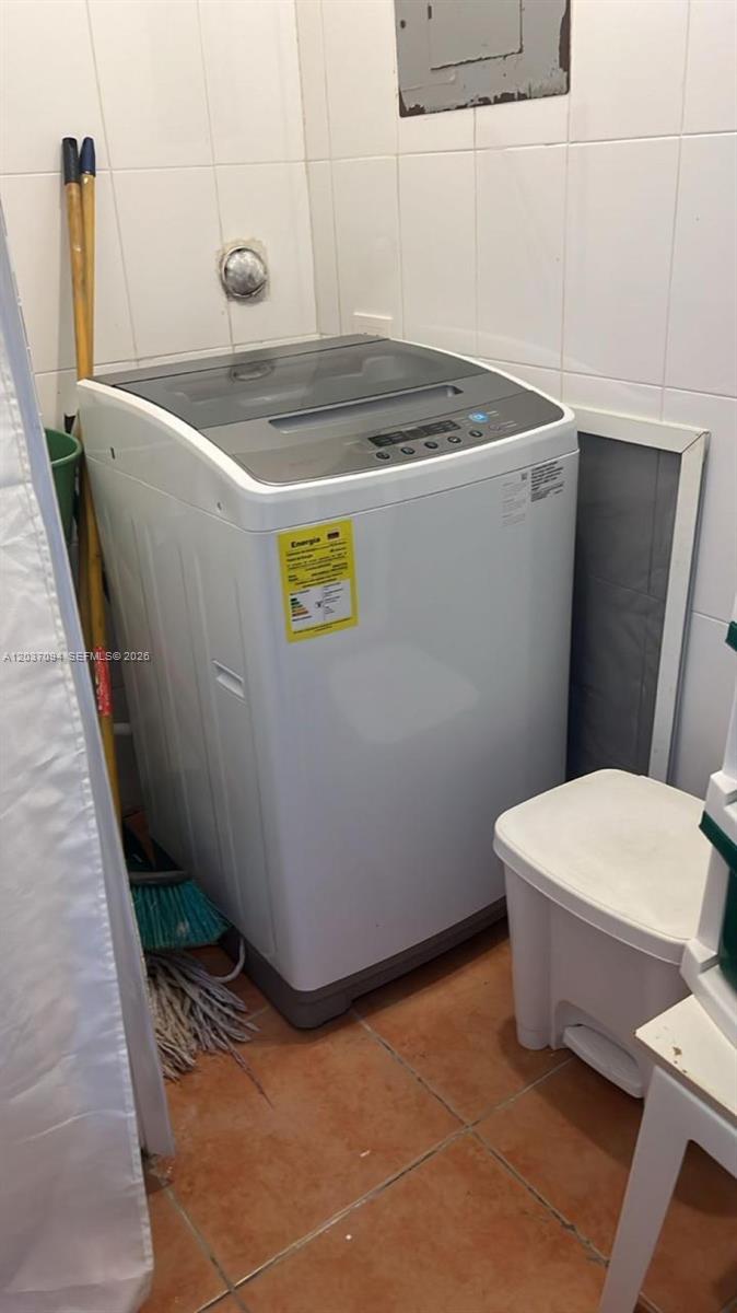 A white top-loading washing machine sits in a tiled laundry room next to a trash can — 0 Bávaro # 0, FL, FL