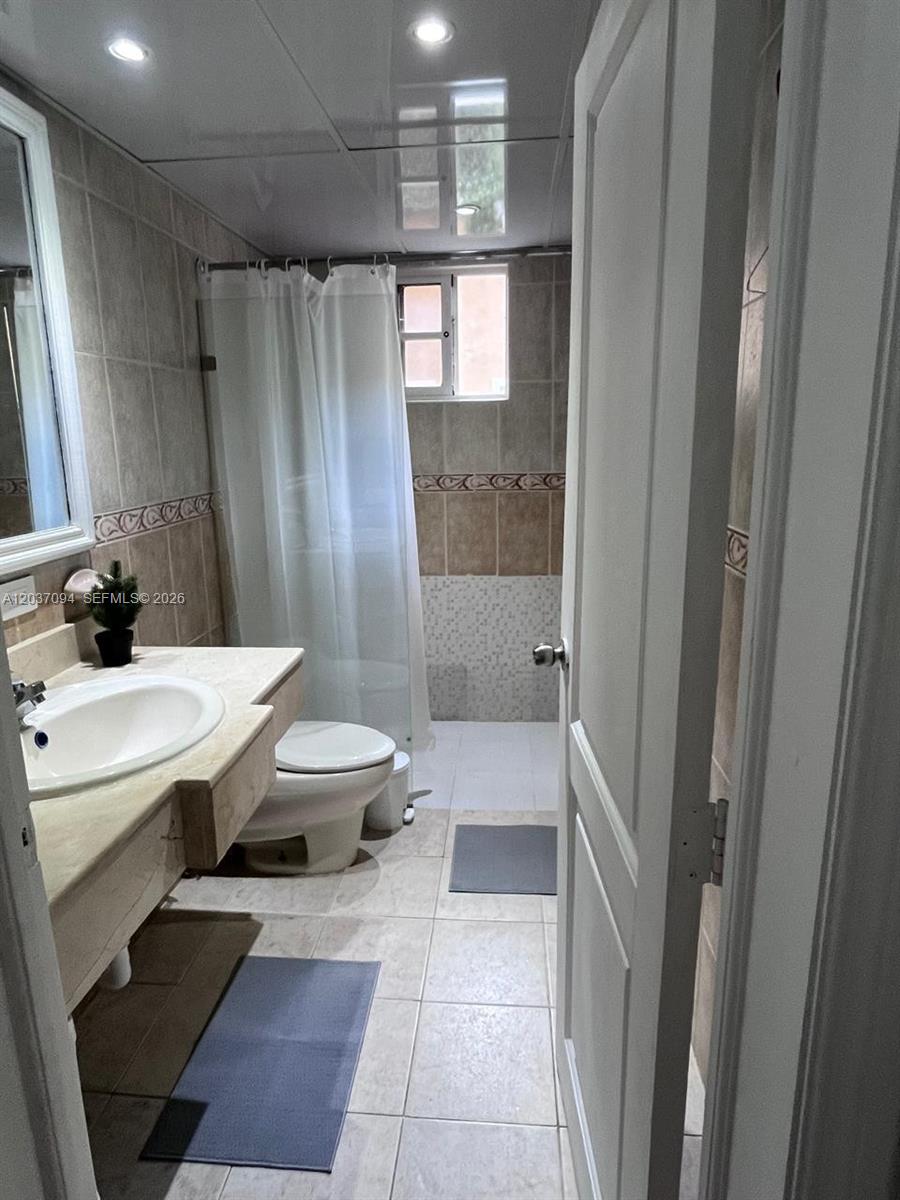 A bathroom features a vanity with a sink, a toilet, and a shower with curtains — 0 Bávaro # 0, FL, FL