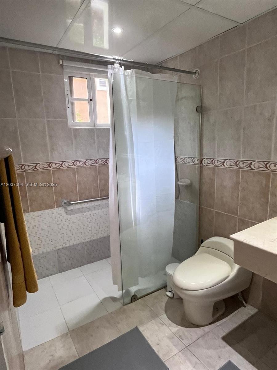 A bathroom features a walk-in shower with a glass panel, a toilet, and tiled walls — 0 Bávaro # 0, FL, FL