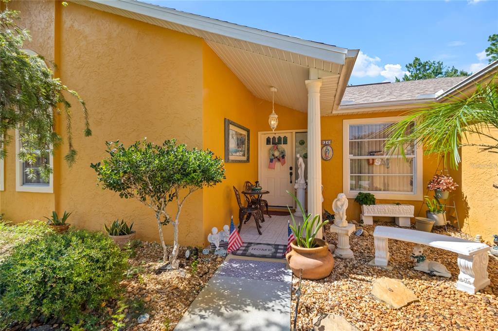 The exterior of a yellow house features a covered entryway with a white column — 24 FOSTER LANE, PALM COAST, FL