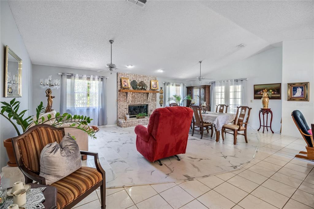 A living and dining room features a brick fireplace, tiled floors, and a red recliner — 24 FOSTER LANE, PALM COAST, FL