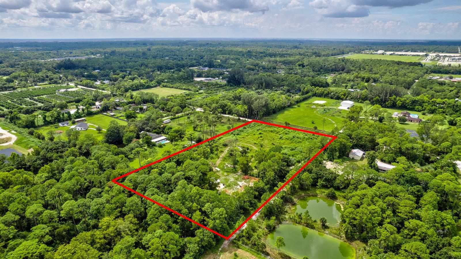An aerial view shows a rectangular plot of land outlined in red amidst wooded surroundings — 15532 43rd Road N, FL 33470, FL