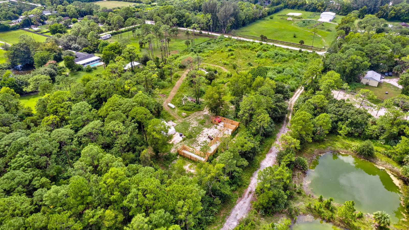 An aerial view shows a wooded lot with a partially constructed wooden building frame — 15532 43rd Road N, FL 33470, FL
