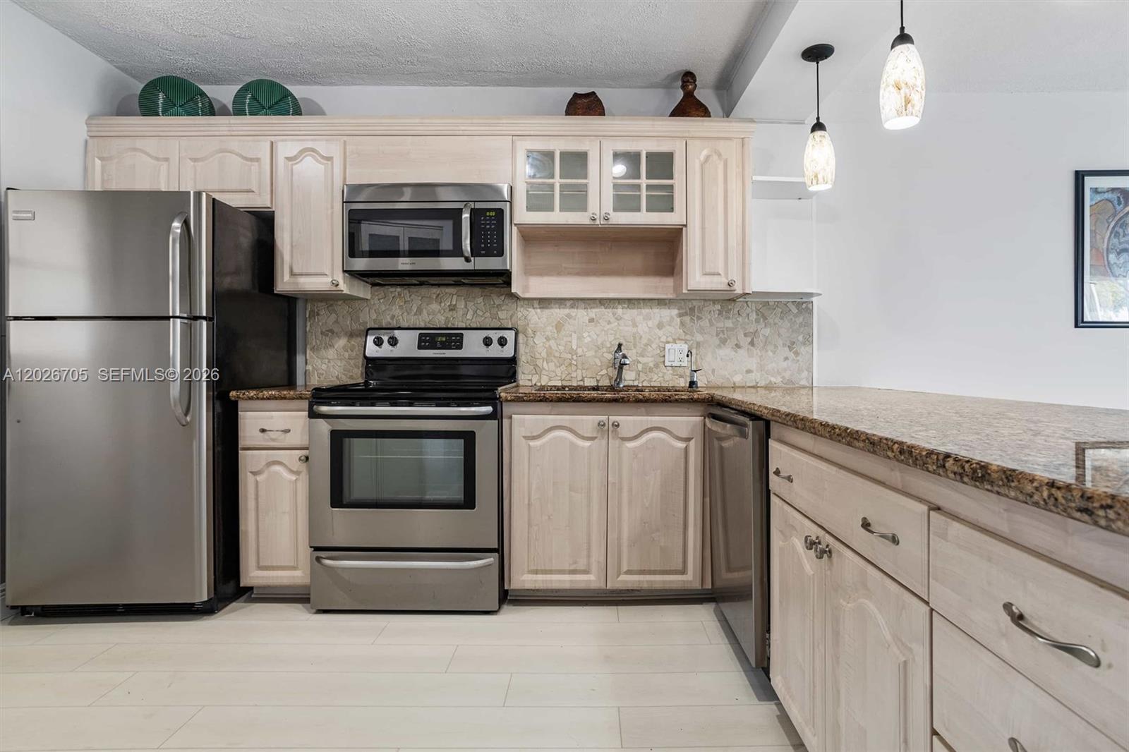 A kitchen features light wood cabinets, stainless steel appliances, and a granite countertop — 2651 S Course Dr # 201, Pompano Beach FL 33069, POMPANO BEACH, FL