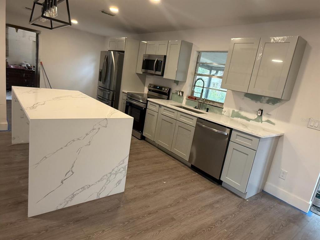 A modern kitchen features light gray cabinets, white marble-patterned countertops, and a large waterfall island — 3621 HAWTHORNE LANE, WINTER PARK, FL