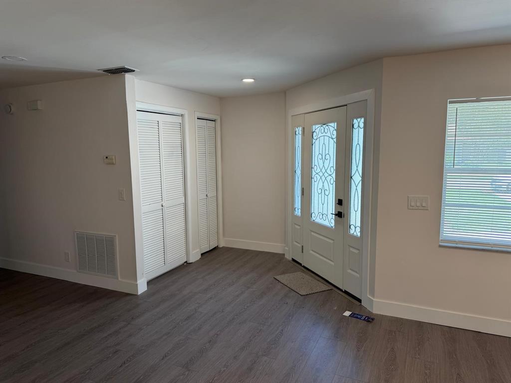 An entryway with wood-look flooring, two louvered closets, and a white front door with sidelights — 3621 HAWTHORNE LANE, WINTER PARK, FL