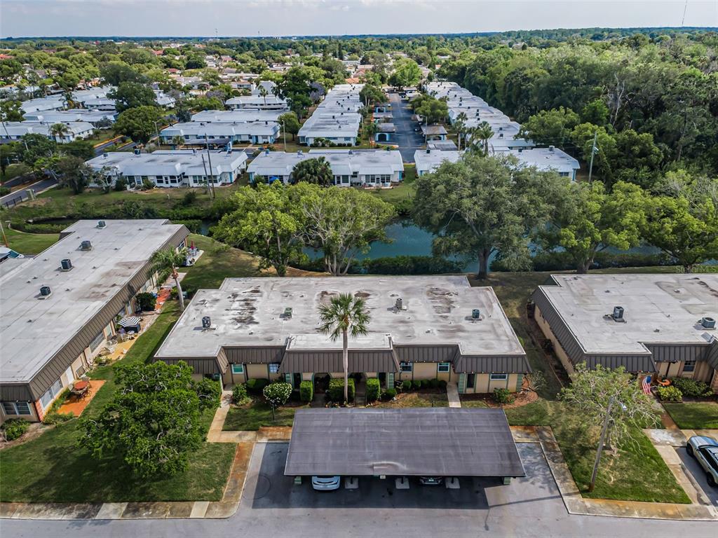 An aerial view shows a residential complex with flat-roofed buildings, a central pond, and carports — 4200 HAMPTON DRIVE, NEW PORT RICHEY, FL