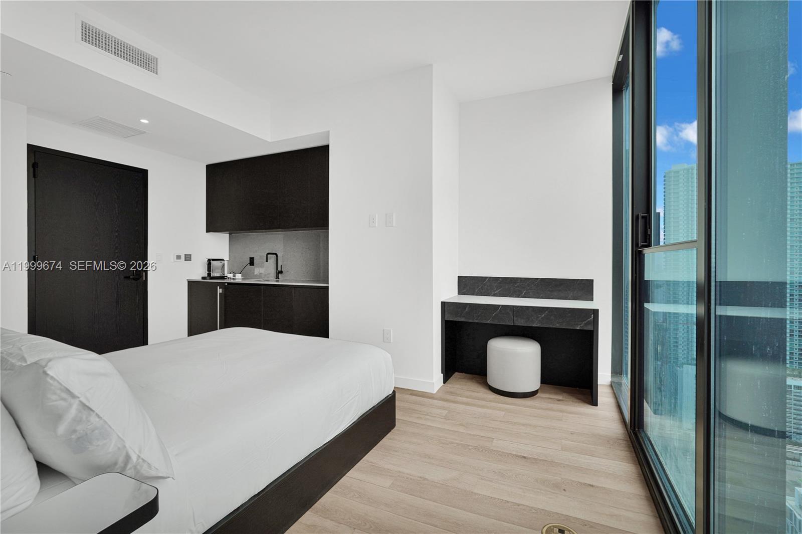A modern bedroom features a kitchenette, a desk, and floor-to-ceiling windows with city views — 20 NE 11th St # 3110, Miami FL 33132, MIAMI, FL
