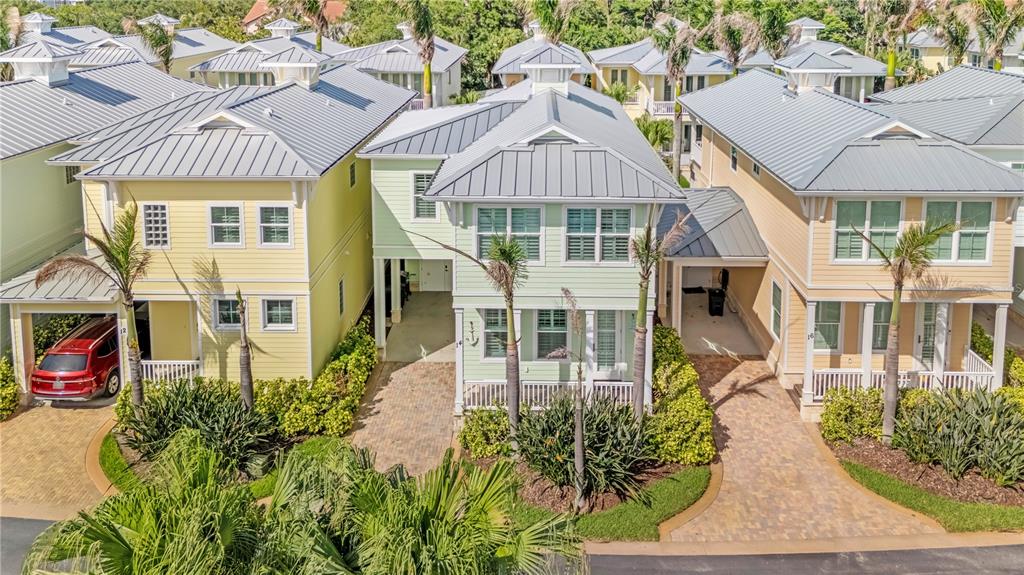 An aerial view shows three coastal-style houses with metal roofs and paved driveways — 14 OLD FEGER DRIVE, NEW SMYRNA BEACH, FL