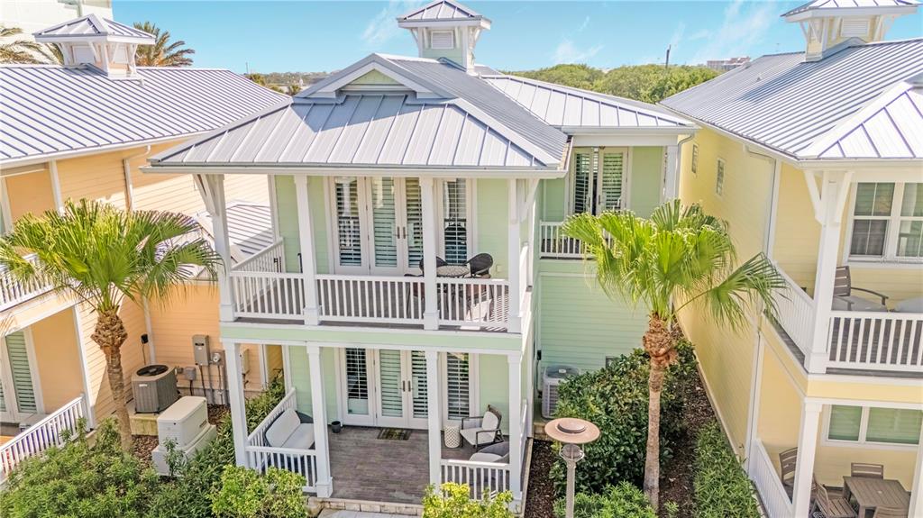 A light green two-story house features a metal roof, white railings, and two palm trees — 14 OLD FEGER DRIVE, NEW SMYRNA BEACH, FL