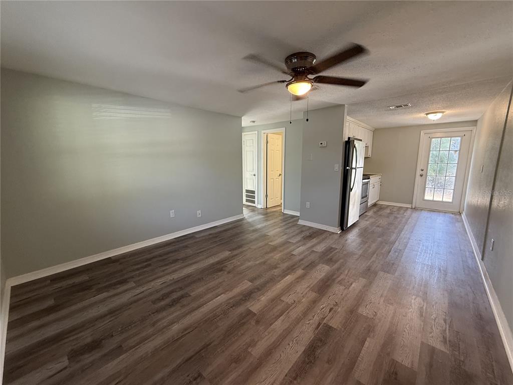 An open-concept living area with wood-look flooring, a ceiling fan, and an adjacent kitchen — 350 ELMSTREET COURT UNIT 6, ENGLEWOOD, FL