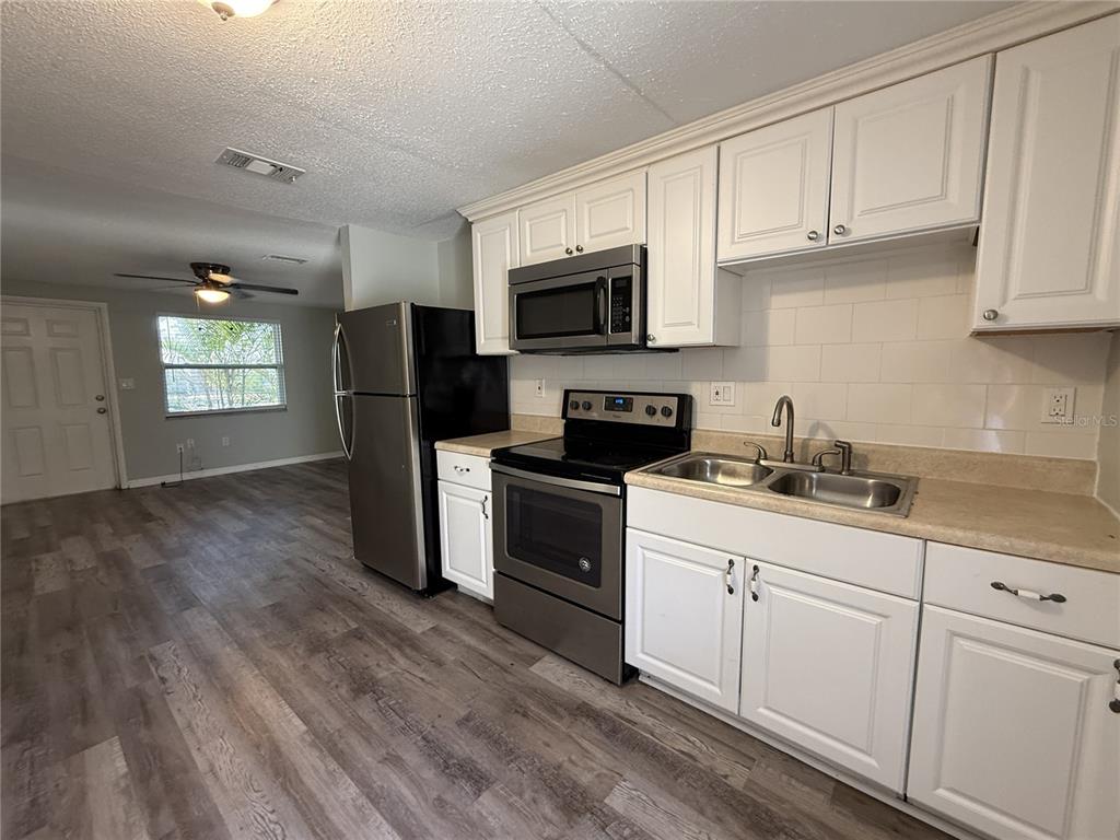 A kitchen features white cabinets, stainless steel appliances, and wood-look flooring — 350 ELMSTREET COURT UNIT 6, ENGLEWOOD, FL