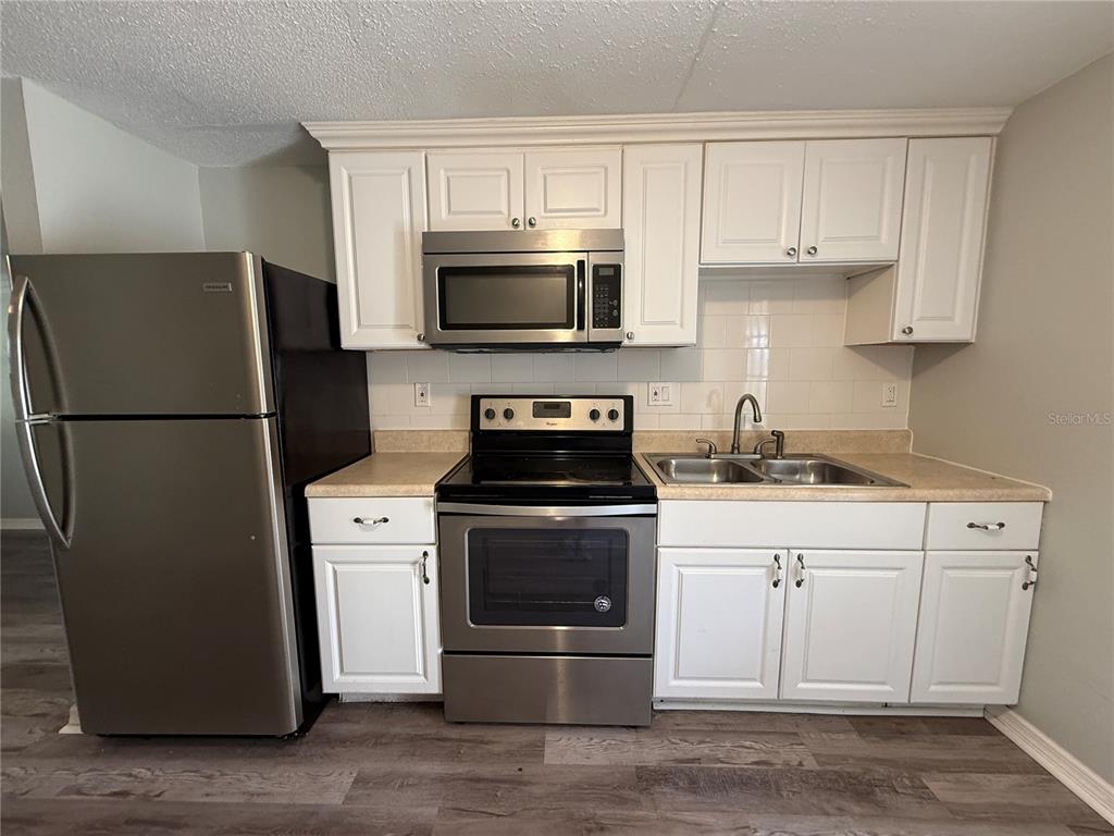 A kitchen with white cabinets, stainless steel appliances, and light-colored countertops — 350 ELMSTREET COURT UNIT 6, ENGLEWOOD, FL