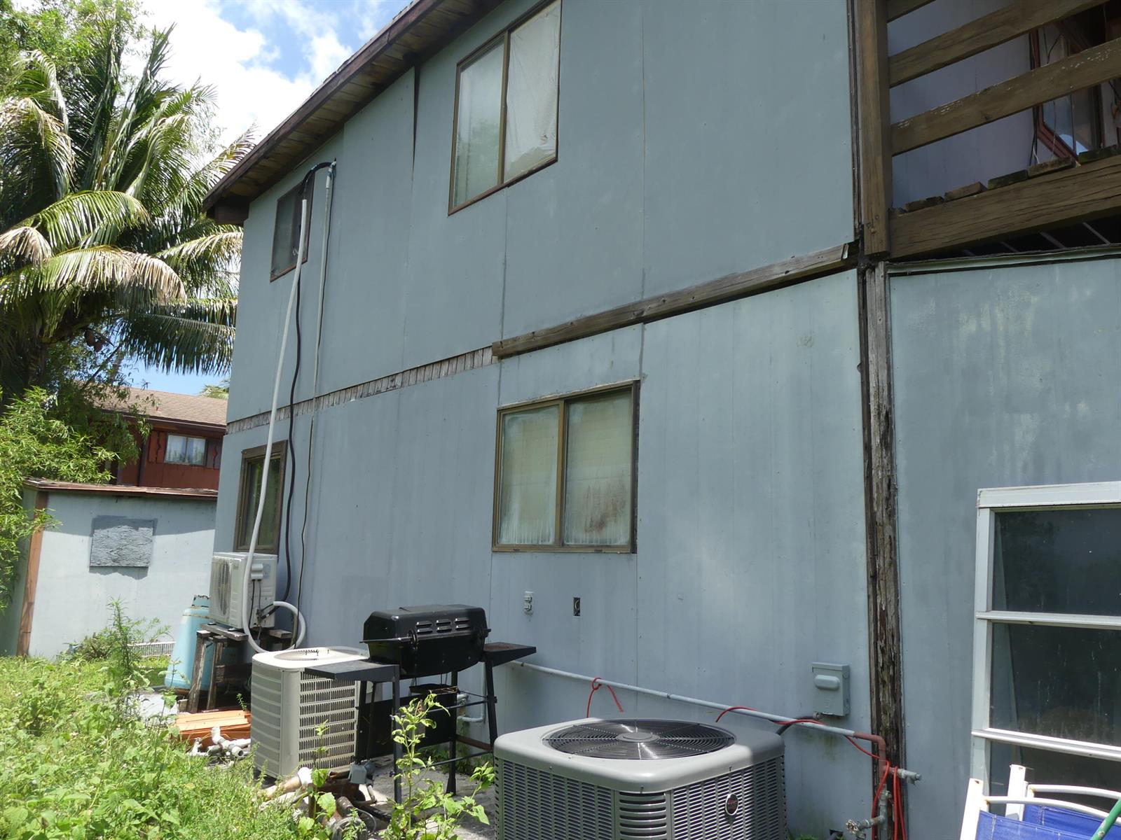 The exterior of a two-story house features blue siding, multiple windows, and two air conditioning units — 6665 Rigger Road, Lake Worth FL 33462, LAKE WORTH, FL
