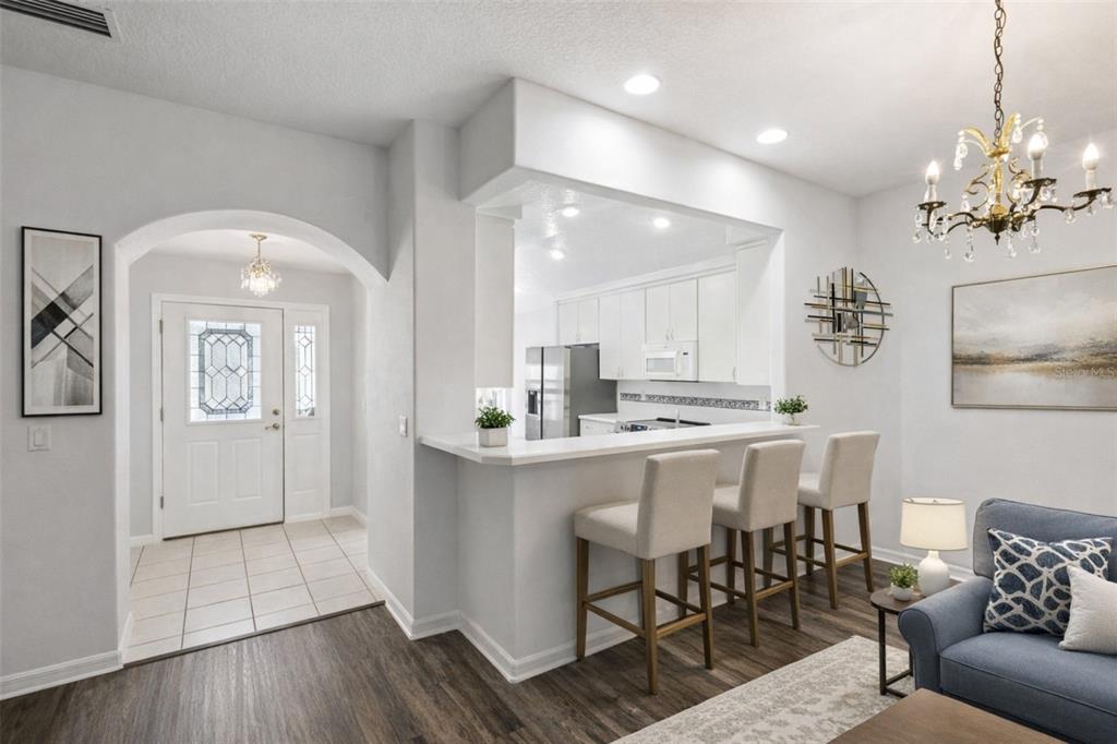 A kitchen with white cabinets and a breakfast bar opens into a living area — 5964 BRITTANIA BOULEVARD, TAVARES, FL