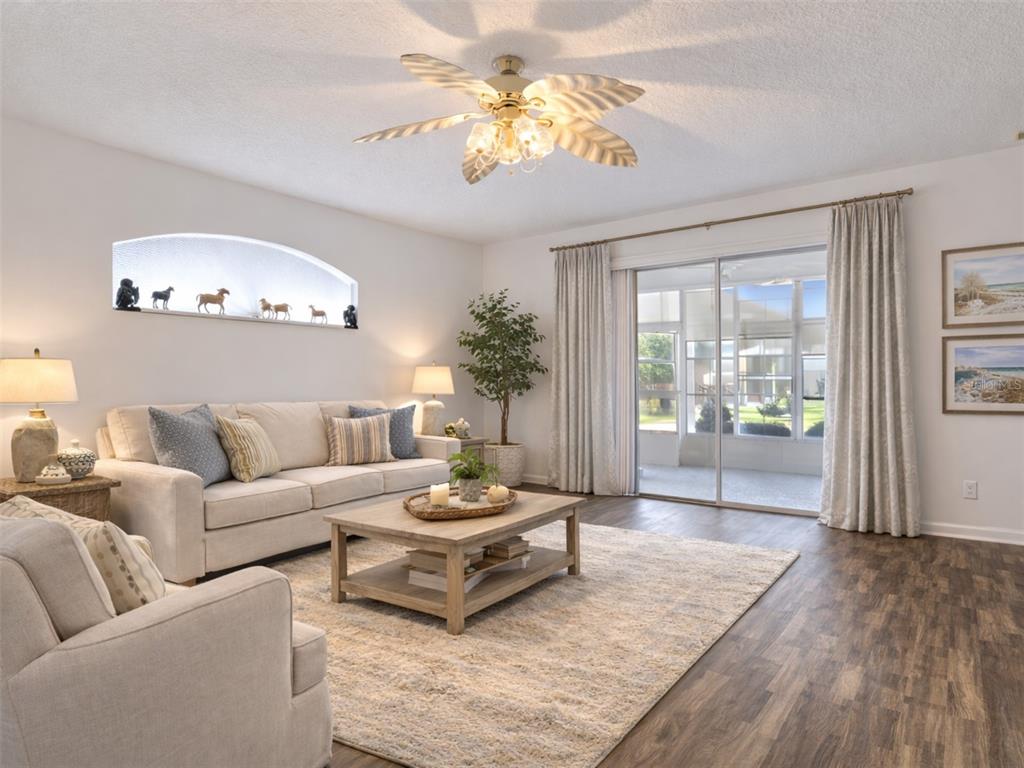 A living room features a beige sofa, wooden coffee table, ceiling fan, and sliding glass doors — 5964 BRITTANIA BOULEVARD, TAVARES, FL