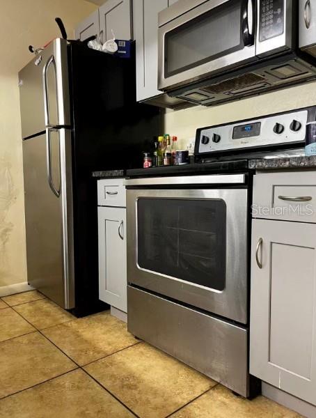 A kitchen features stainless steel appliances, light gray cabinets, and tan tile flooring — 3800 SW 20TH AVENUE UNIT 306, GAINESVILLE, FL
