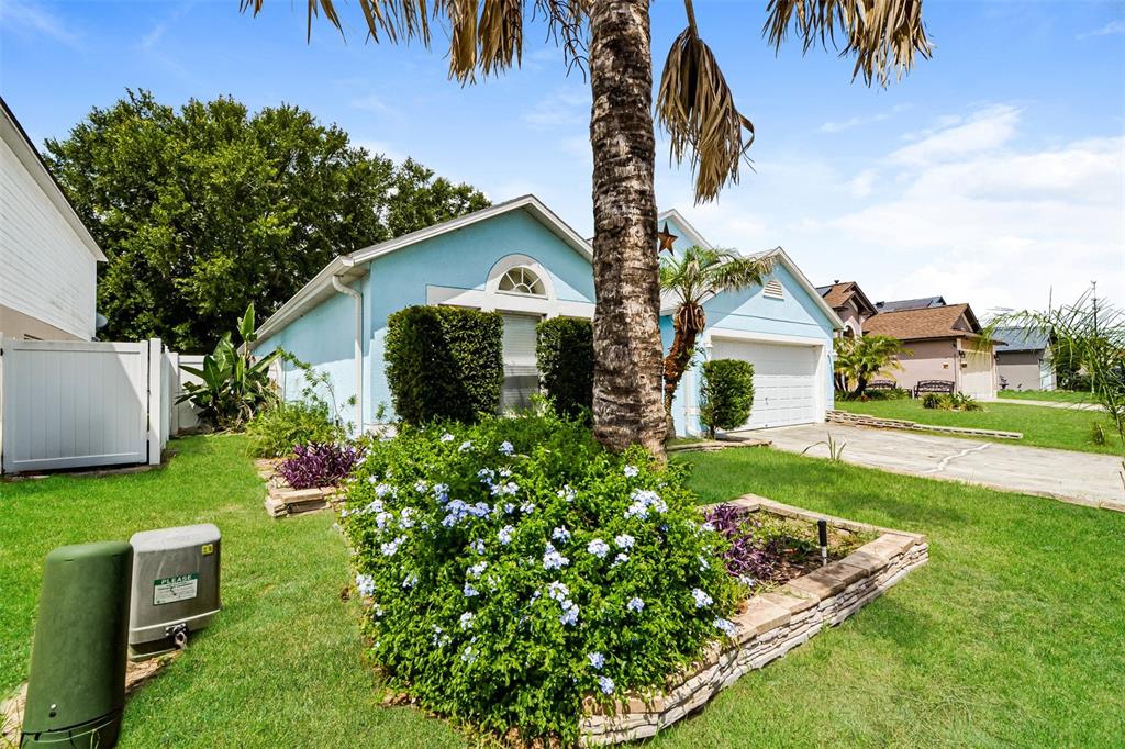 A light blue house with a palm tree and a stone-bordered garden in the front yard — 207 RONALDALE AVENUE, HAINES CITY, FL