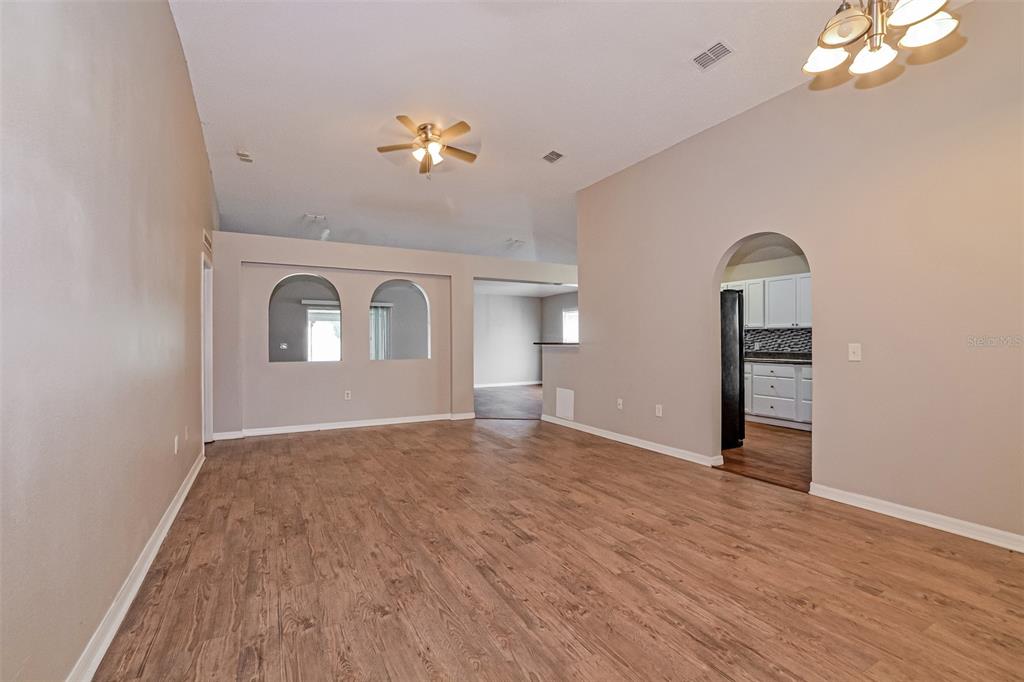 An open living area features wood-look flooring, arched wall cutouts, and a kitchen visible through an archway — 207 RONALDALE AVENUE, HAINES CITY, FL