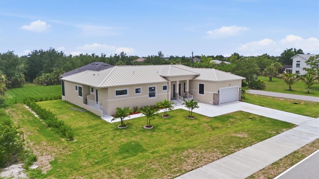 An aerial view shows a single-story house with a metal roof and a concrete driveway — 14491 INGRAHAM BOULEVARD, PORT CHARLOTTE, FL