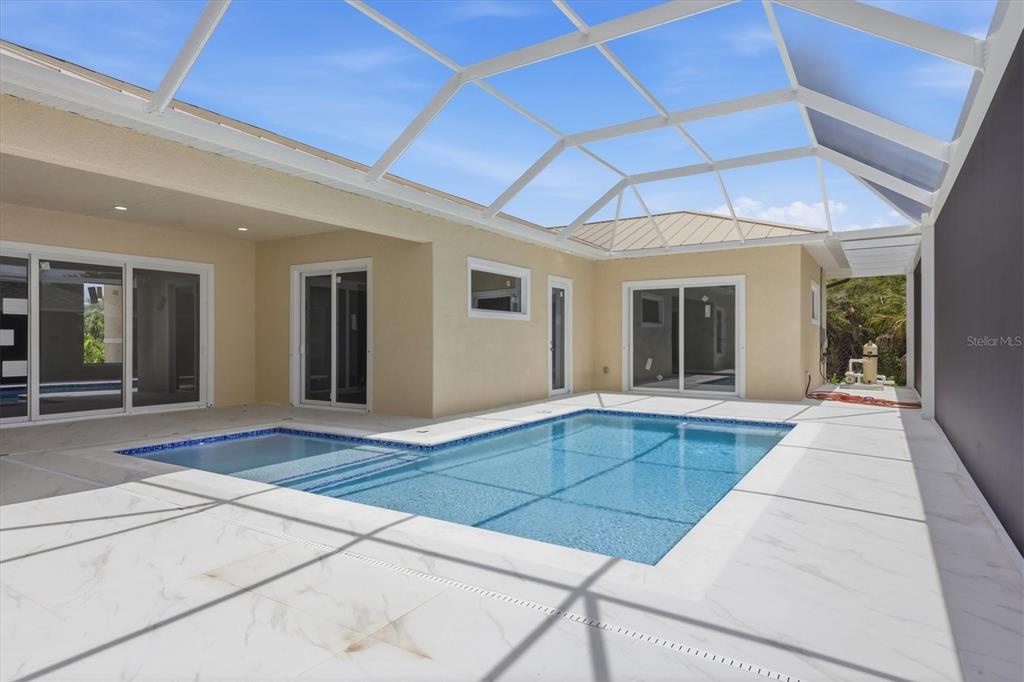 A screened-in patio features a swimming pool with a spa on a light-colored tiled deck — 14491 INGRAHAM BOULEVARD, PORT CHARLOTTE, FL