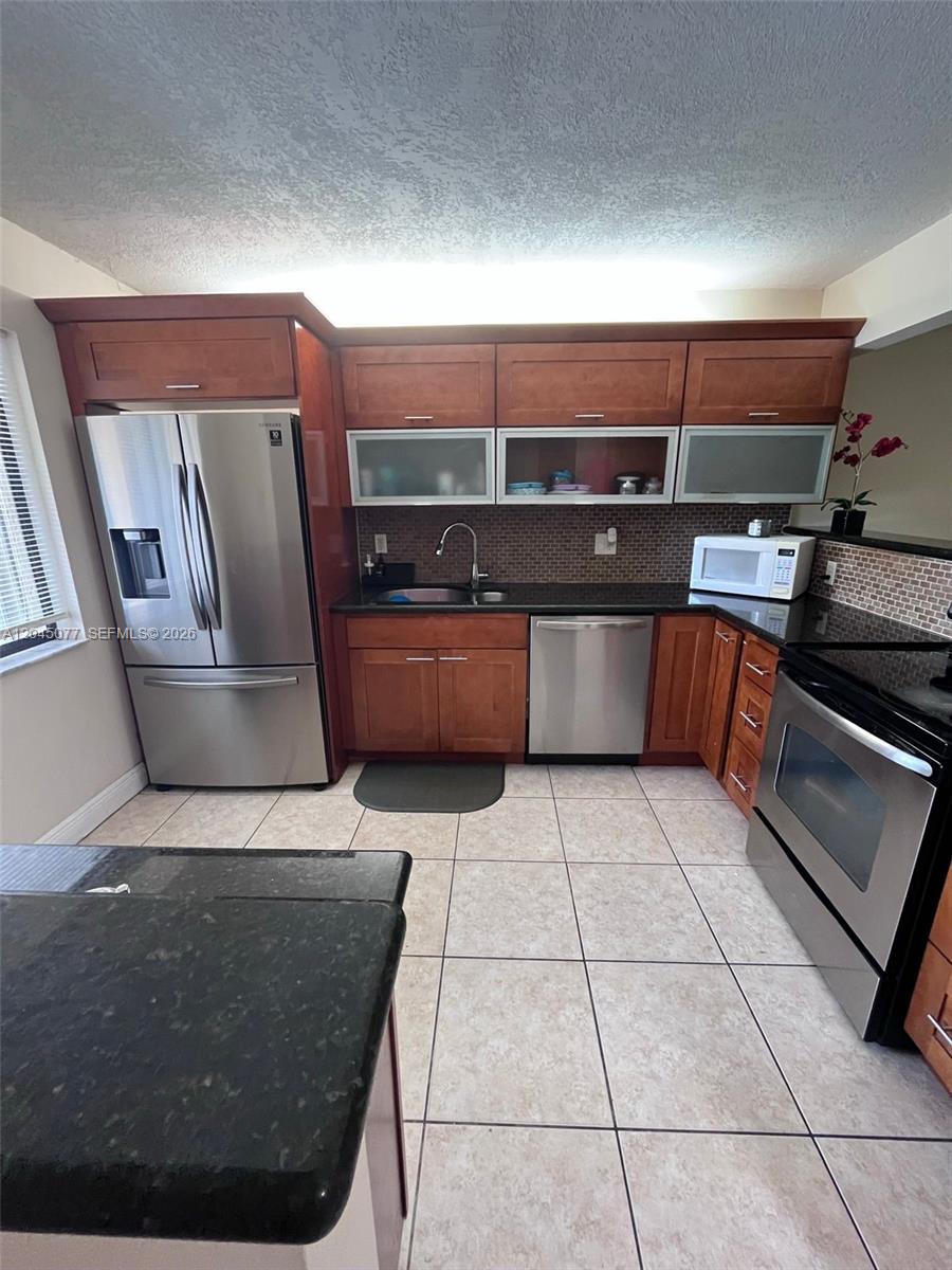 A tiled entryway leads to a front door and a window on a stucco wall — 197 Lakeview Dr # 105, Weston FL 33326, WESTON, FL