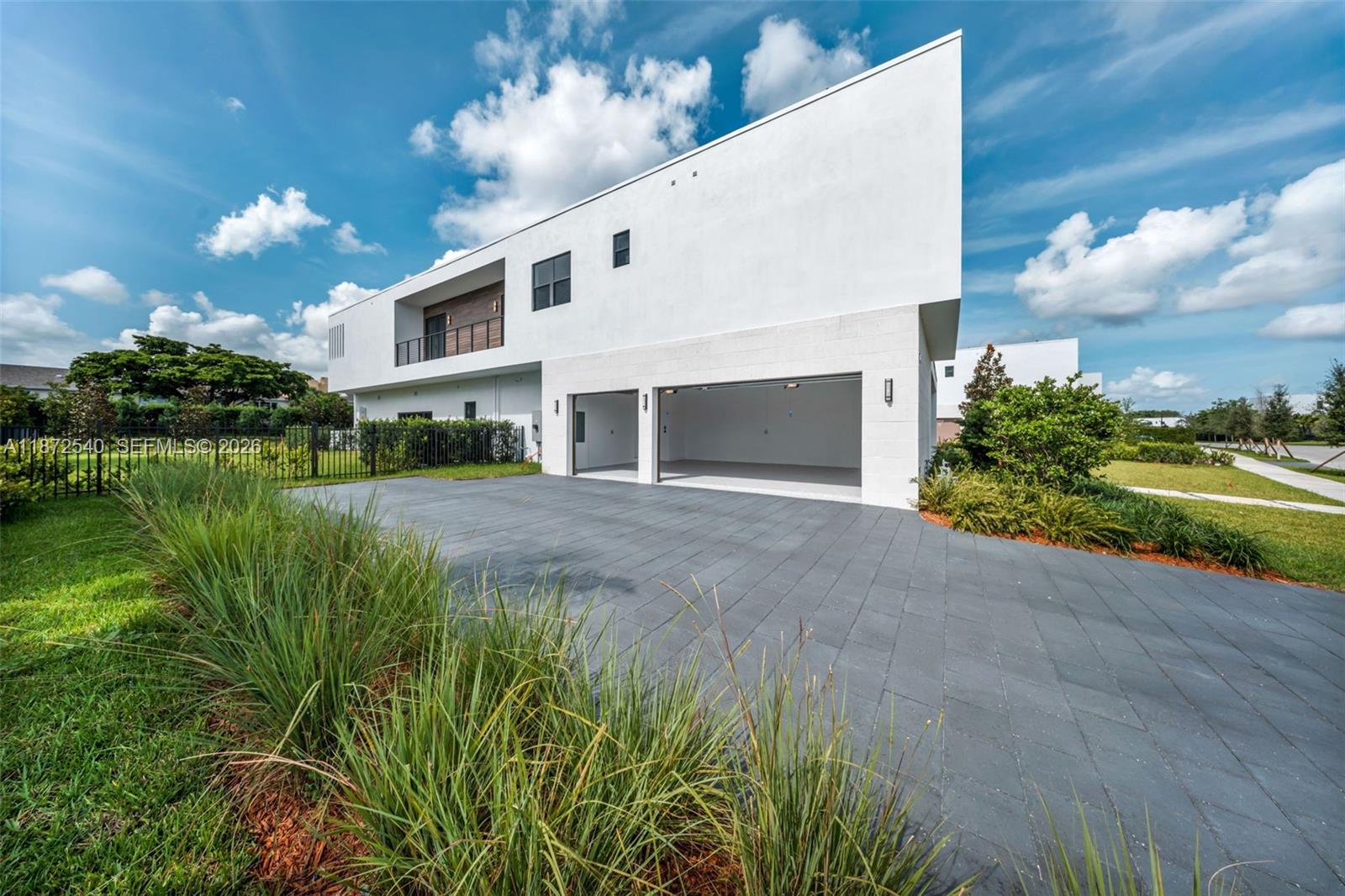 A modern white two-story house features a two-car garage and a paved driveway — 16740 N Botaniko Dr N, Weston FL 33326, WESTON, FL