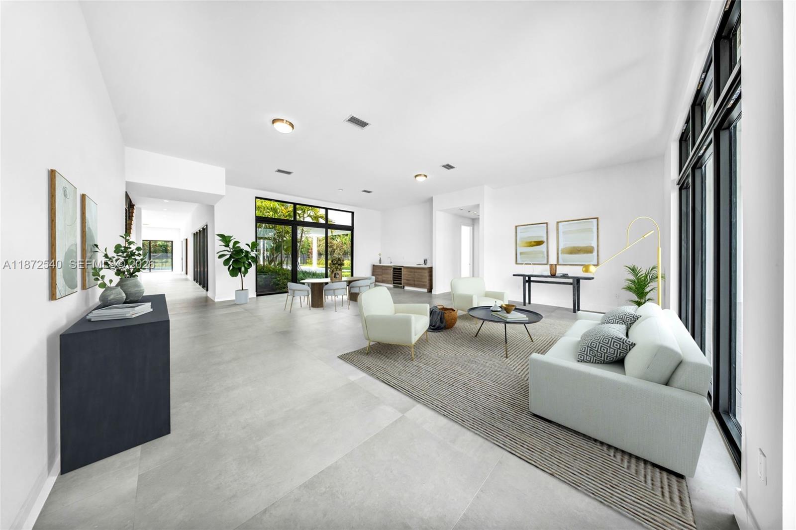 A spacious, modern living and dining area features white walls, large windows, and tile flooring — 16740 N Botaniko Dr N, Weston FL 33326, WESTON, FL