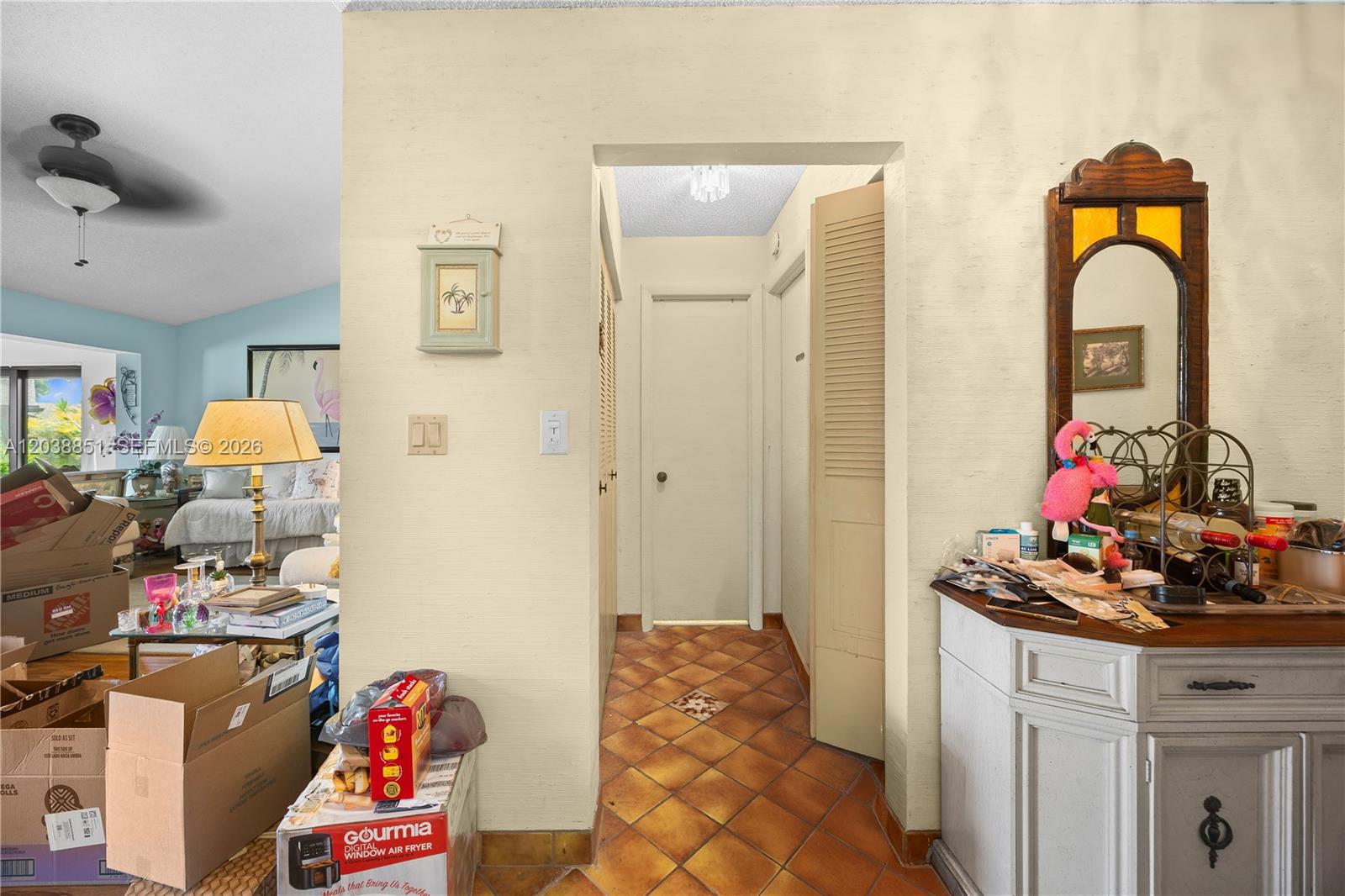 A hallway with terracotta tile flooring leads to a closed door between two rooms — 2065 SW 17th Dr, Deerfield Beach FL 33442, DEERFIELD BEACH, FL
