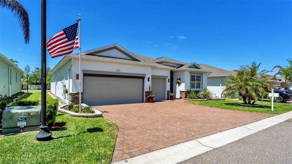 A single-story house features a brick paver driveway, a two-car garage, and an American flag — 3890 BEDFORD AVENUE, WINTER HAVEN, FL