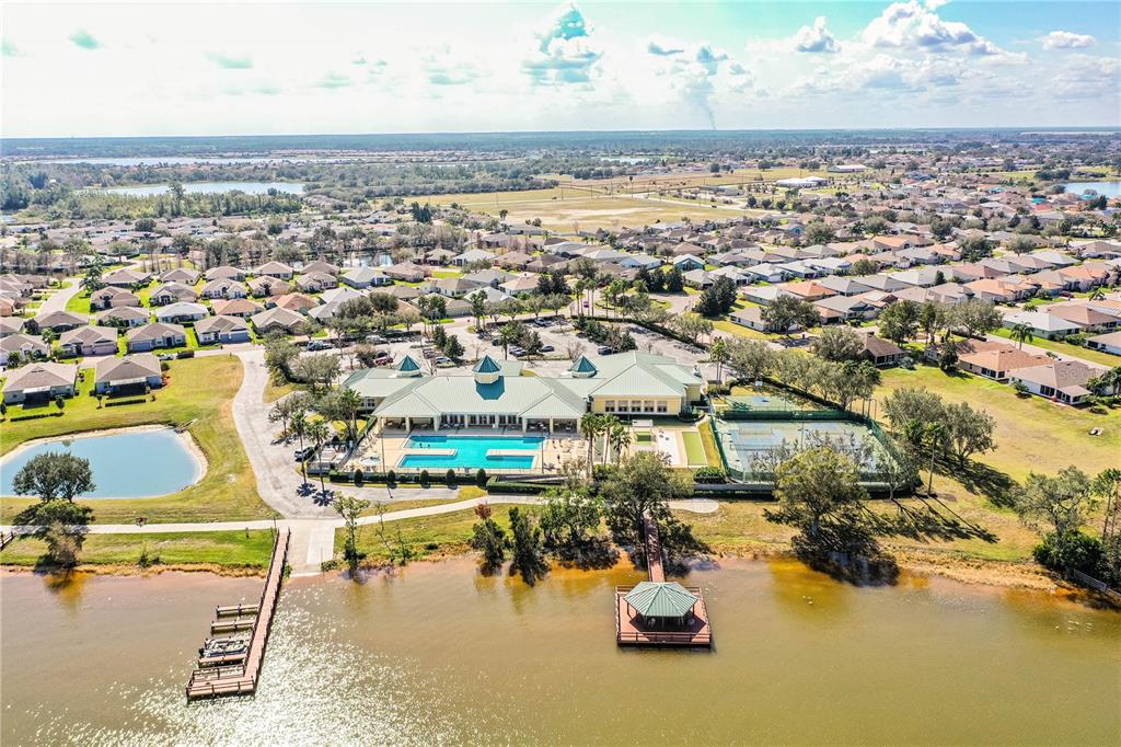 An aerial view of a community clubhouse with a pool, tennis courts, and a lake — 3890 BEDFORD AVENUE, WINTER HAVEN, FL