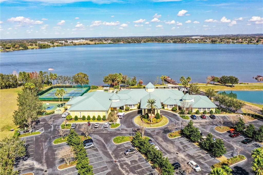 An aerial view shows a clubhouse with a green roof, parking lot, and tennis courts — 3890 BEDFORD AVENUE, WINTER HAVEN, FL