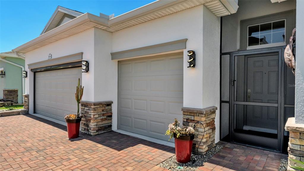 The exterior of a house features two garage doors, stone accents, and a screened entryway — 3890 BEDFORD AVENUE, WINTER HAVEN, FL