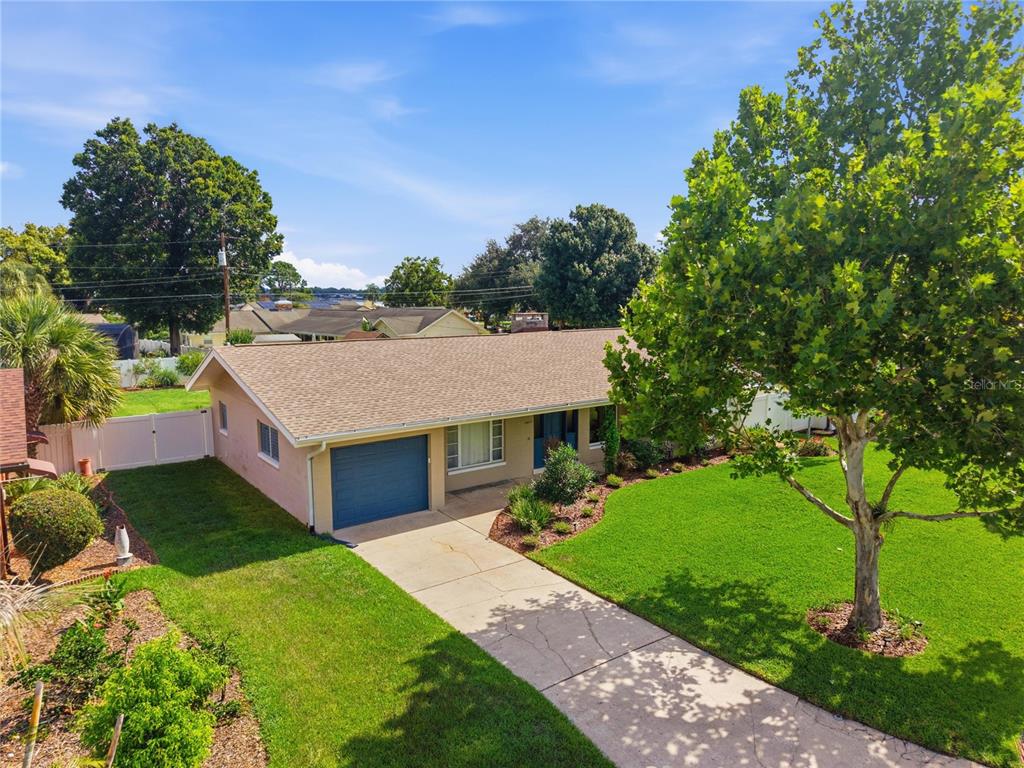 An exterior view of a single-story house with a garage, driveway, and a large tree — 2817 FLOWERTREE ROAD, ORLANDO, FL