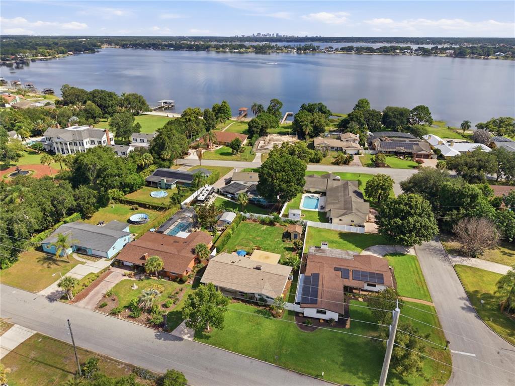 An aerial view shows a residential neighborhood with houses, swimming pools, and a large lake — 2817 FLOWERTREE ROAD, ORLANDO, FL