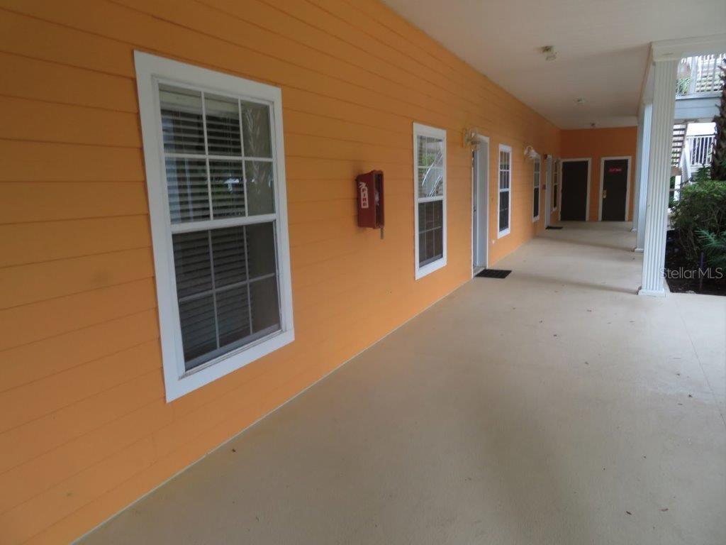 A long, covered outdoor walkway features orange siding, white-trimmed windows, and a red fire extinguisher — 603 NEW PROVIDENCE UNIT 603, DAVENPORT, FL