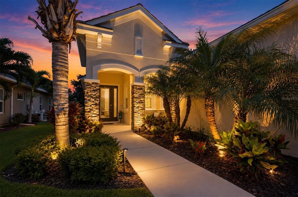 A paved walkway leads to the front entrance of a house with stone-accented columns — 4209 MIDNIGHT BLUE RUN, BRADENTON, FL